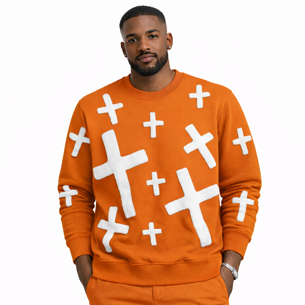 Man wearing an orange gravity sweater with white cross patterns on a white background