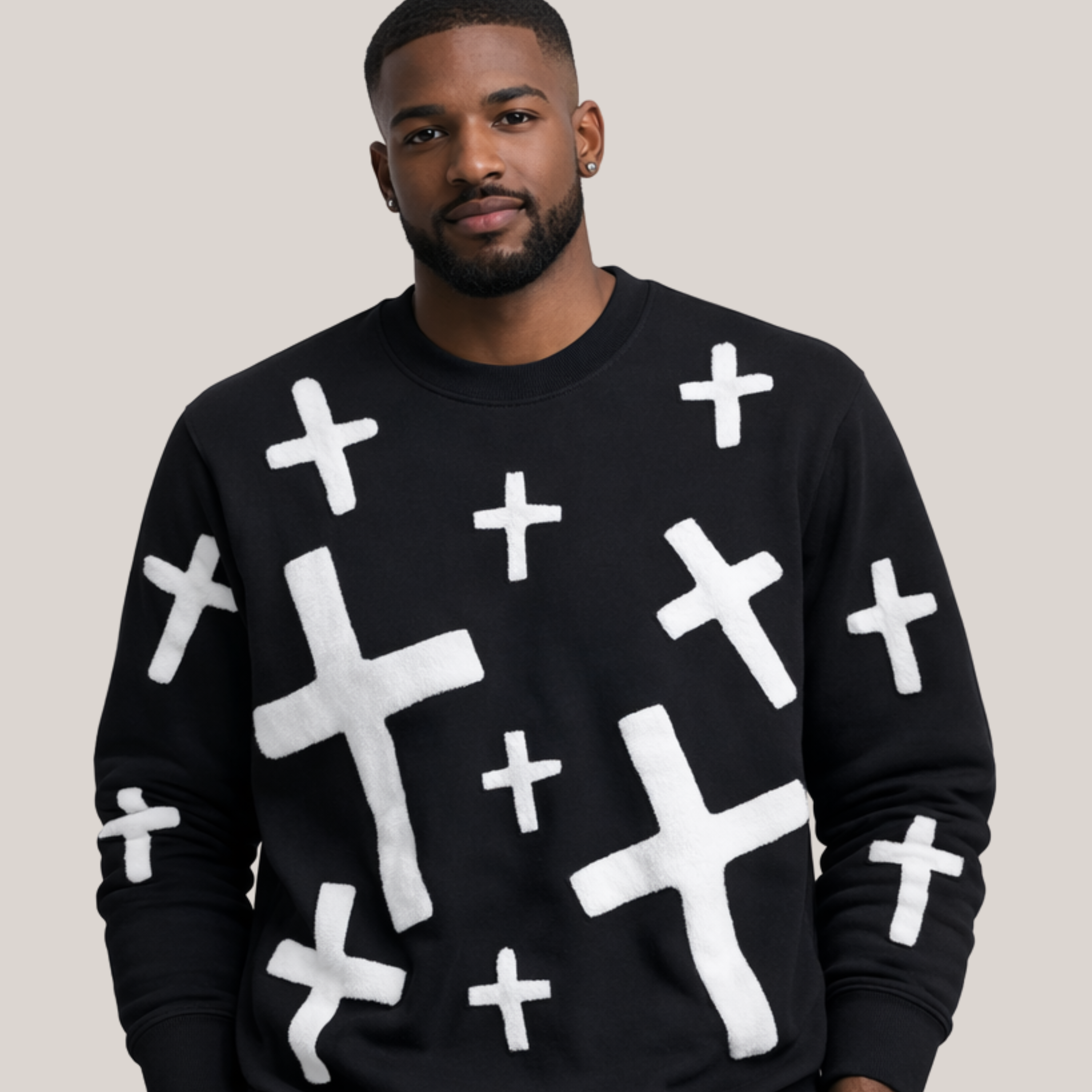 Man wearing a black sweater with white cross patterns on a plain background